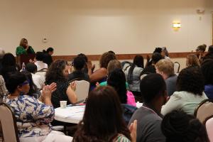 Woman presenting to a group of people, people are clapping for her