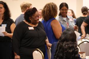 Woman smiling in a group of people talking to one another