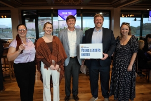 Photo of 5 individuals posing at cocktails and conversations, one man is holding a sign that says Young Leaders United