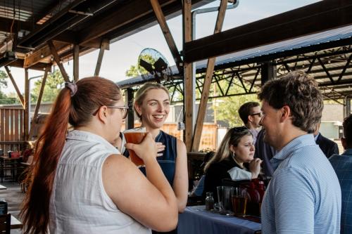 Photo of a group of three people talking at the last YLU Happy Hour. One of the girls is smiling and mid-conversation.