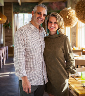 Photo of Ryan and Kelleanne Jones, inside of a restaurant and smiling at the camera