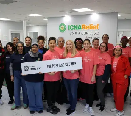 Photo of volunteers from The Post and Courier and staff at the Shifa Clinic standing together in a group and smiling at the camera.