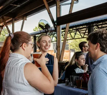 Photo of a group of three people talking at the last YLU Happy Hour. One of the girls is smiling and mid-conversation.