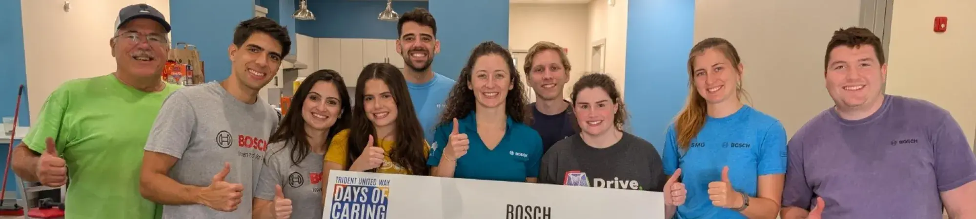 A group of volunteers for Days of Caring posing for the camera holding a sign that says Bosch