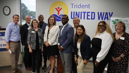 Board members stand smiling and looking at the camera in the lobby of the North Charleston Center for Strong Families.
