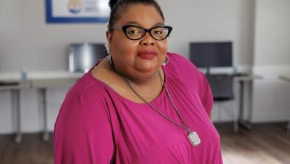 Racheal Williams is wearing a pink shirt and long necklace, standing in the Dorchester Center for Strong Families