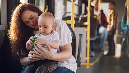 A woman sits with her baby on her lap on the bus.