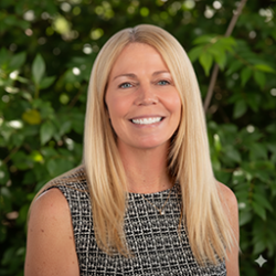 Alisha stands in front of trees smiling at the camera.